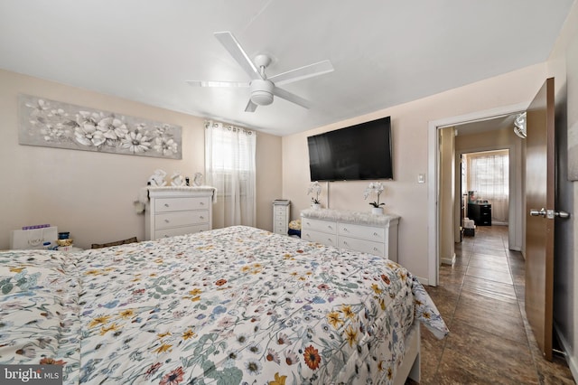 bedroom with ceiling fan, multiple windows, and baseboards