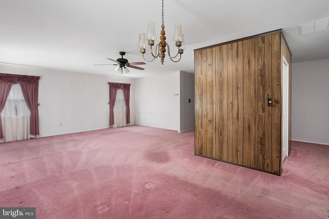 spare room featuring carpet, visible vents, and ceiling fan with notable chandelier