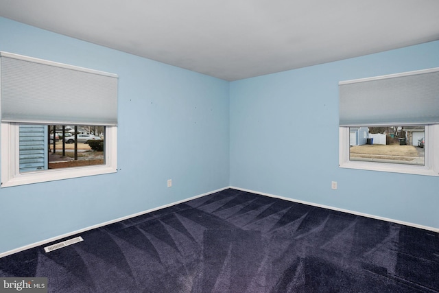 empty room with carpet, visible vents, and baseboards