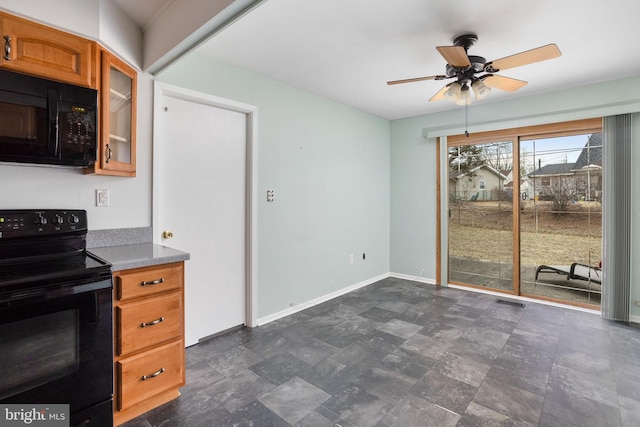 kitchen with baseboards, brown cabinetry, a ceiling fan, glass insert cabinets, and black appliances