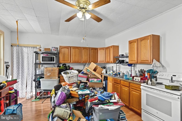 kitchen with electric range, stainless steel microwave, light wood-type flooring, and brown cabinets