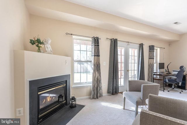 living area with a fireplace with flush hearth, baseboards, and carpet floors