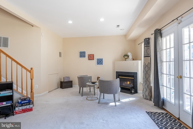 living area featuring french doors, carpet floors, and stairs