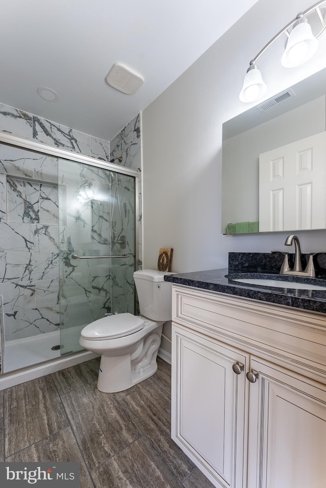 full bath featuring a marble finish shower, toilet, visible vents, and vanity