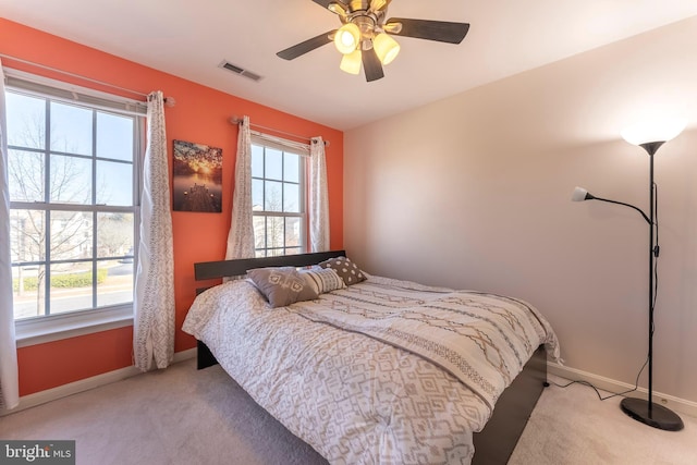 bedroom with light carpet, visible vents, multiple windows, and baseboards