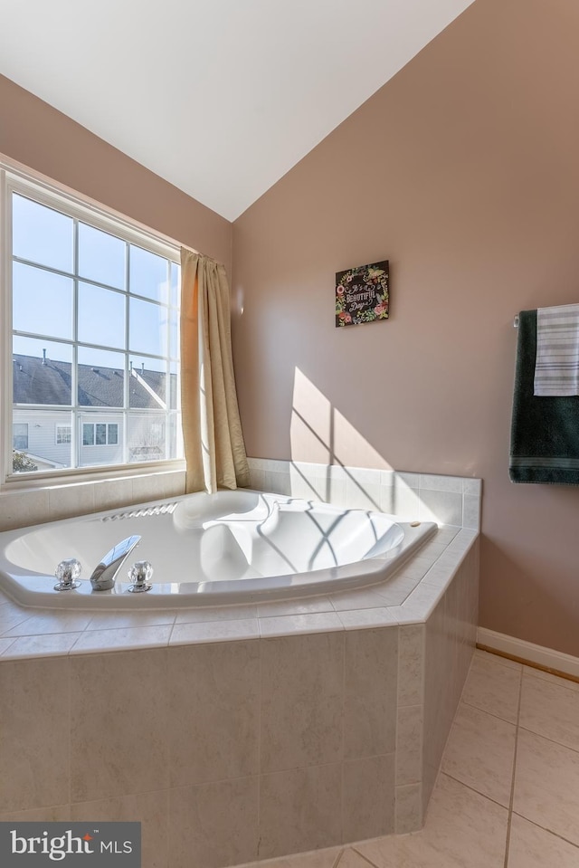 bathroom with tile patterned flooring, baseboards, a bath, and lofted ceiling