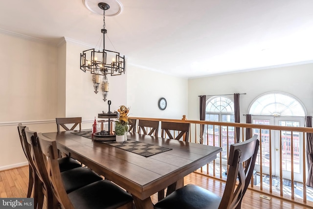 dining space with a notable chandelier, crown molding, light wood-type flooring, and baseboards