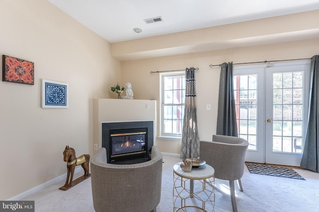 living area with visible vents, baseboards, a multi sided fireplace, carpet floors, and french doors