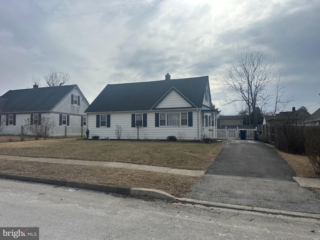 view of front of house with a gate, fence, aphalt driveway, and a front yard