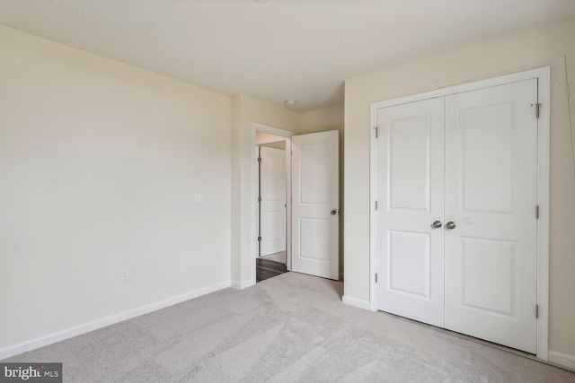 unfurnished bedroom with a closet, carpet, and baseboards