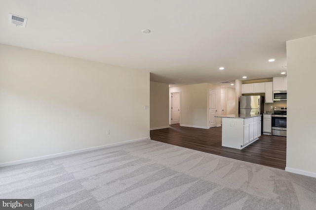 interior space with baseboards, visible vents, dark wood-style flooring, dark carpet, and recessed lighting