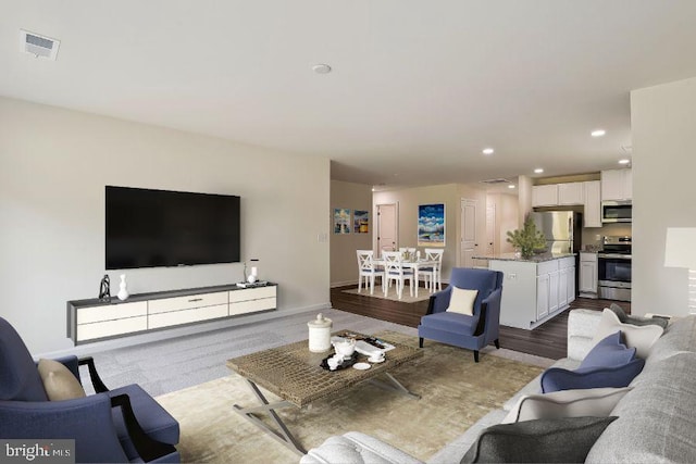 living room featuring recessed lighting, visible vents, baseboards, and wood finished floors