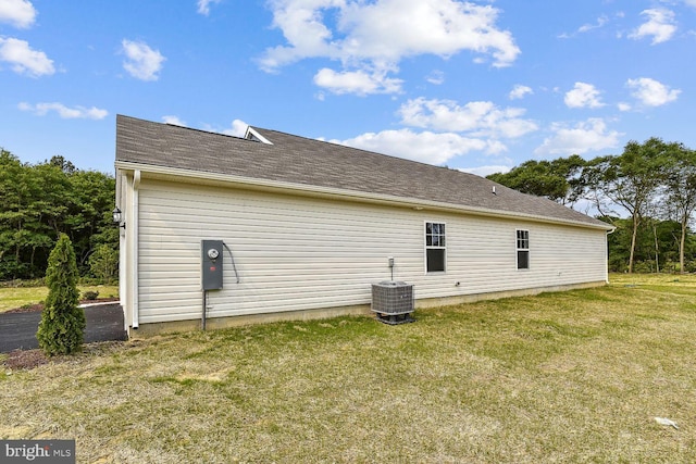 view of side of home with a lawn and central air condition unit