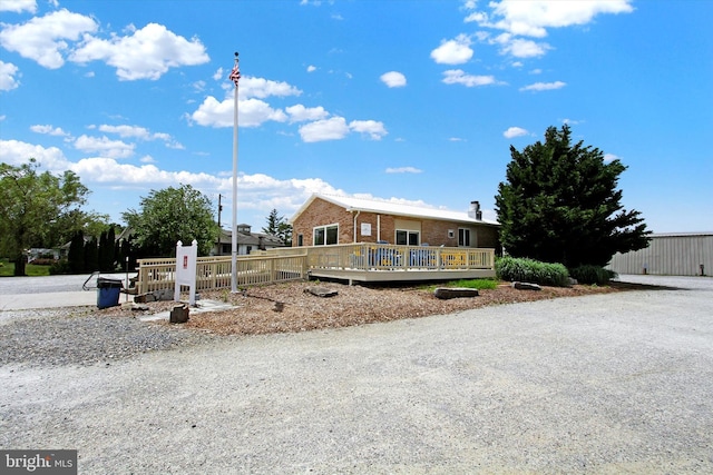 view of front of home with brick siding and a wooden deck