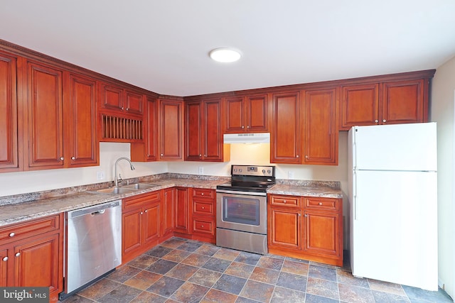 kitchen with light countertops, appliances with stainless steel finishes, stone finish floor, a sink, and under cabinet range hood