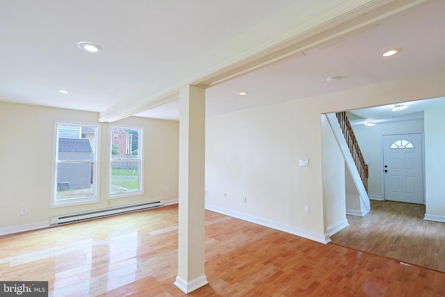 basement with a baseboard radiator, recessed lighting, stairway, light wood-style flooring, and baseboards