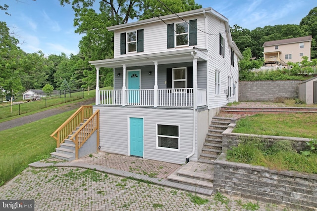 view of front facade with a front yard, covered porch, fence, and stairs