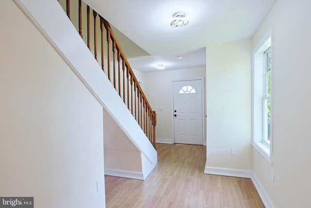 foyer featuring light wood-style flooring, baseboards, and stairs