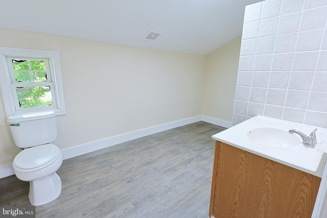 bathroom with baseboards, visible vents, toilet, wood finished floors, and vanity