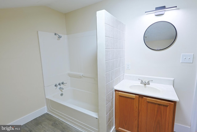 bathroom with baseboards, shower / washtub combination, wood finished floors, and vanity