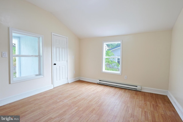 empty room featuring a baseboard heating unit, lofted ceiling, baseboards, and wood finished floors