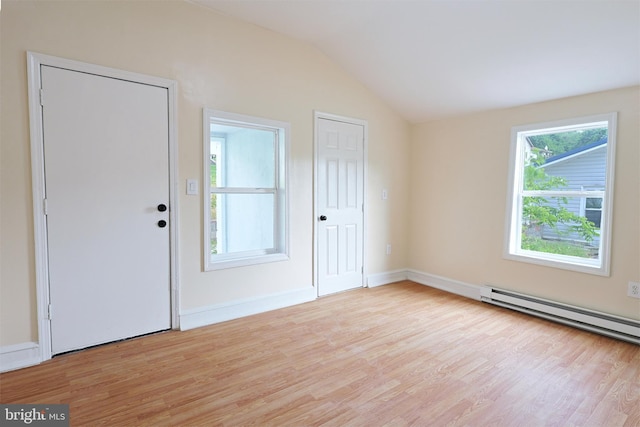 unfurnished room featuring vaulted ceiling, baseboard heating, light wood-type flooring, and baseboards