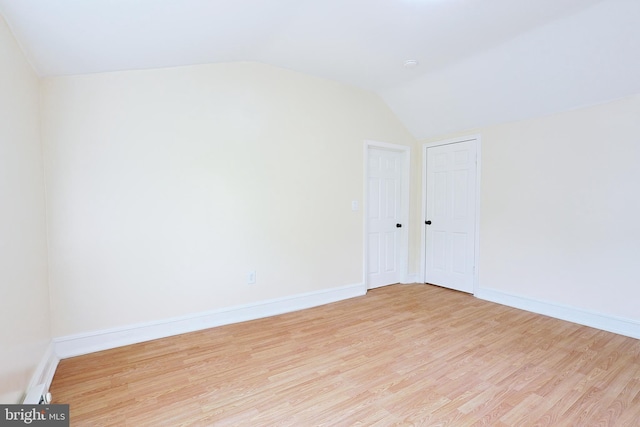 unfurnished room featuring vaulted ceiling, baseboards, and wood finished floors