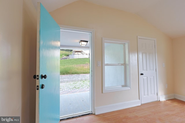 doorway with vaulted ceiling, baseboards, and wood finished floors