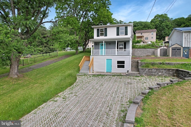 view of front of property featuring stairway, covered porch, an outdoor structure, a shed, and a front lawn