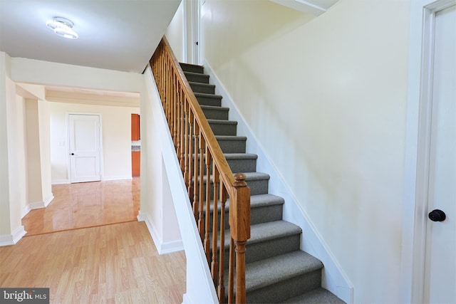 staircase featuring wood finished floors and baseboards