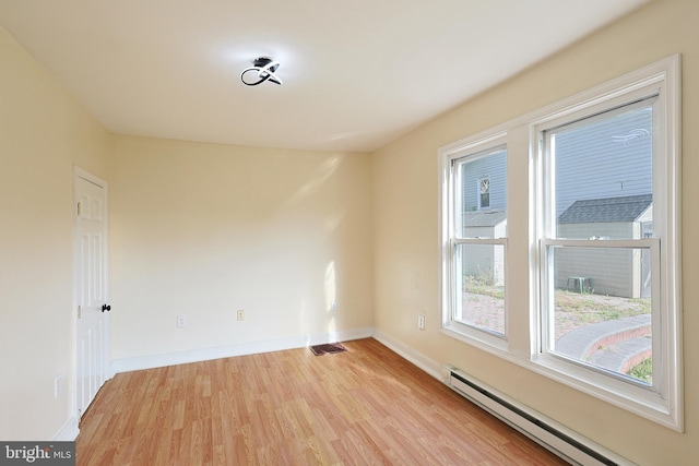 empty room featuring light wood-type flooring, a baseboard radiator, visible vents, and baseboards