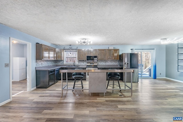 kitchen featuring stainless steel appliances, a sink, backsplash, and light wood finished floors