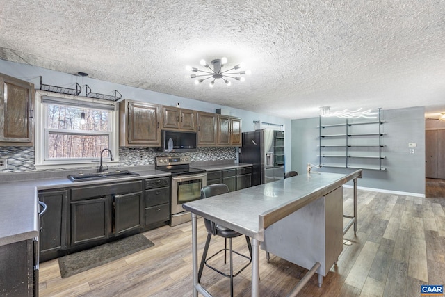 kitchen with light wood-type flooring, appliances with stainless steel finishes, backsplash, and a sink