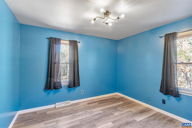 unfurnished room featuring a wealth of natural light, visible vents, and baseboards