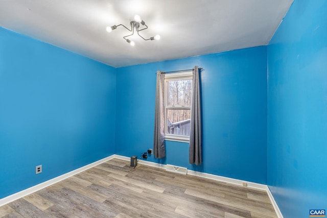 unfurnished room featuring wood finished floors, visible vents, and baseboards