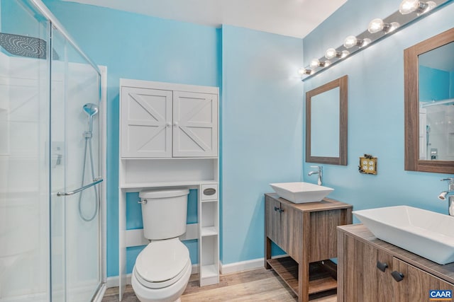 bathroom with a stall shower, a sink, and wood finished floors