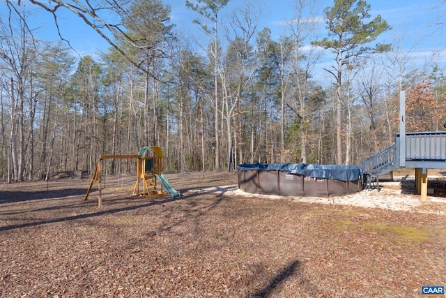 community playground with a covered pool and a view of trees