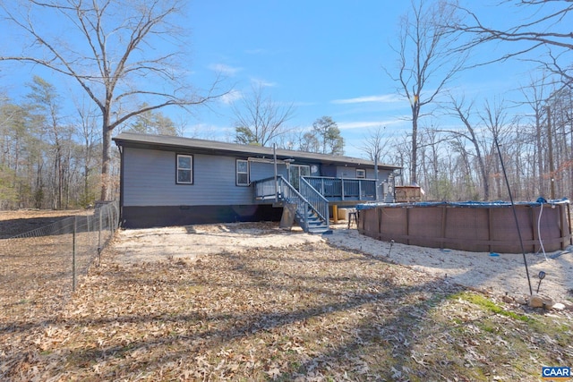 rear view of house featuring a deck, fence, stairs, crawl space, and an outdoor pool