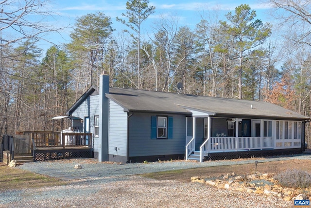 view of front facade with covered porch, crawl space, a chimney, and a wooden deck