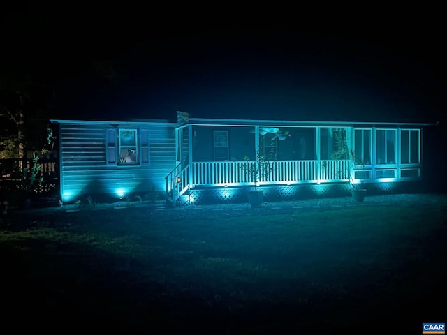 back of house at night featuring a porch