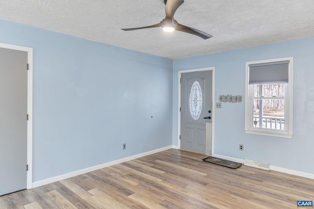 entryway featuring a textured ceiling, ceiling fan, wood finished floors, visible vents, and baseboards