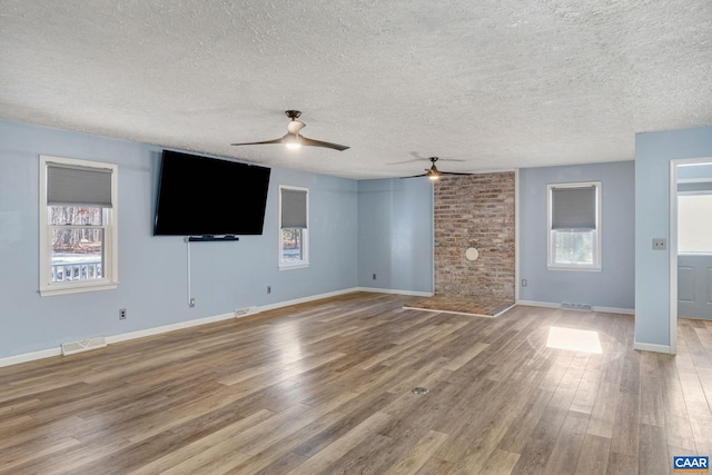 unfurnished living room featuring baseboards, visible vents, a ceiling fan, wood finished floors, and a textured ceiling