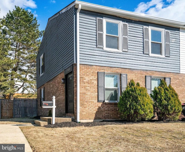 view of home's exterior with brick siding and fence