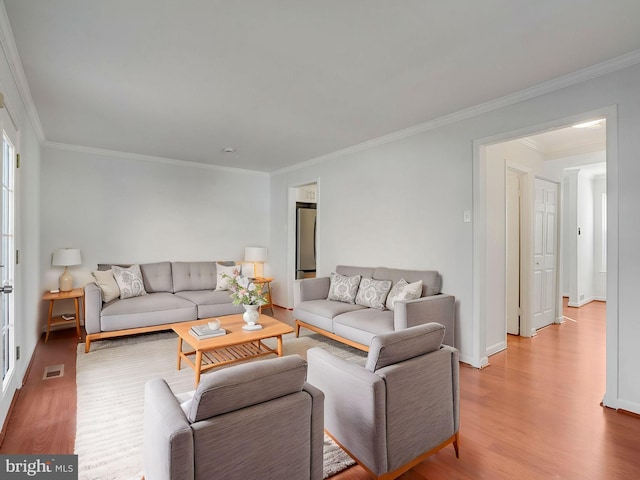 living room featuring visible vents, crown molding, light wood-style flooring, and baseboards