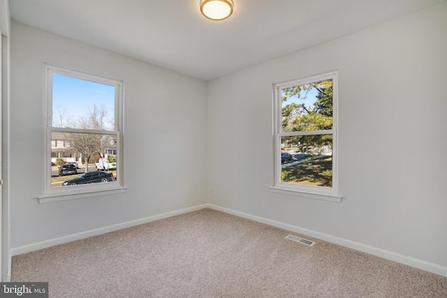 empty room with carpet flooring, visible vents, and baseboards