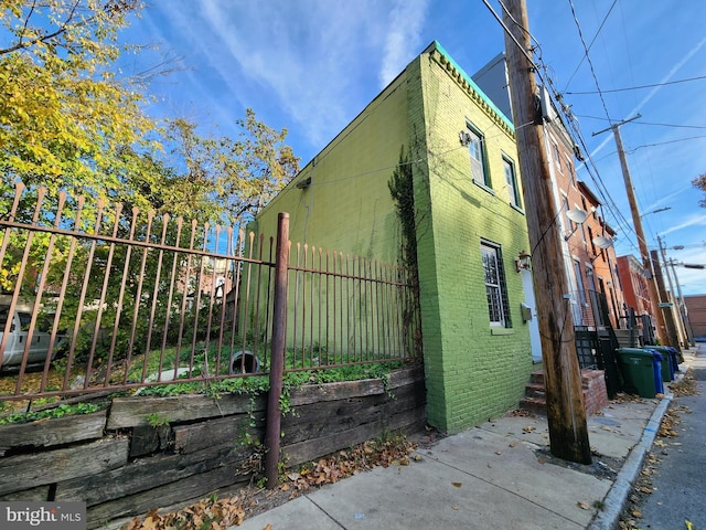 view of side of home featuring a vegetable garden, fence, and brick siding