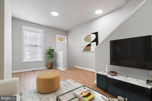 living room featuring light wood-style flooring, visible vents, and baseboards