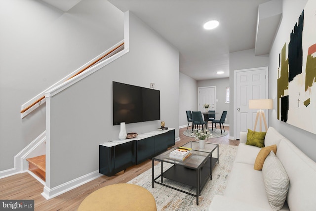 living area featuring stairs, light wood finished floors, recessed lighting, and baseboards