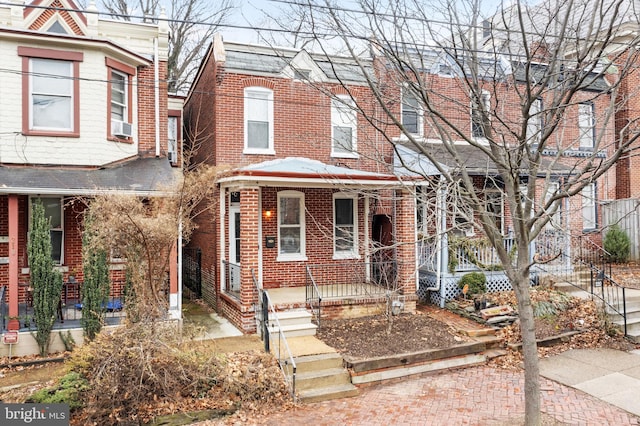 townhome / multi-family property with covered porch, cooling unit, and brick siding