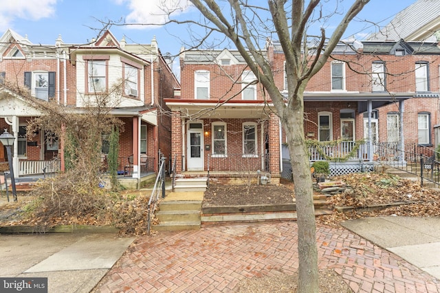 townhome / multi-family property featuring a porch and brick siding